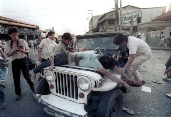 A wounded protester is laid on the hood of a press vehicle to be rushed to a nearby hospital. Luis Liwanag
